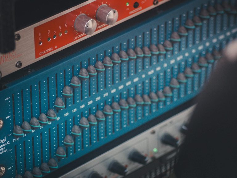 Detailed view of a professional audio equalizer with knobs and controls in a recording studio.